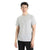A person with short black hair wears the Icebreaker Mens Tech Lite II SS Tee in light gray and black pants, standing against a white background and facing the camera with a neutral expression.
