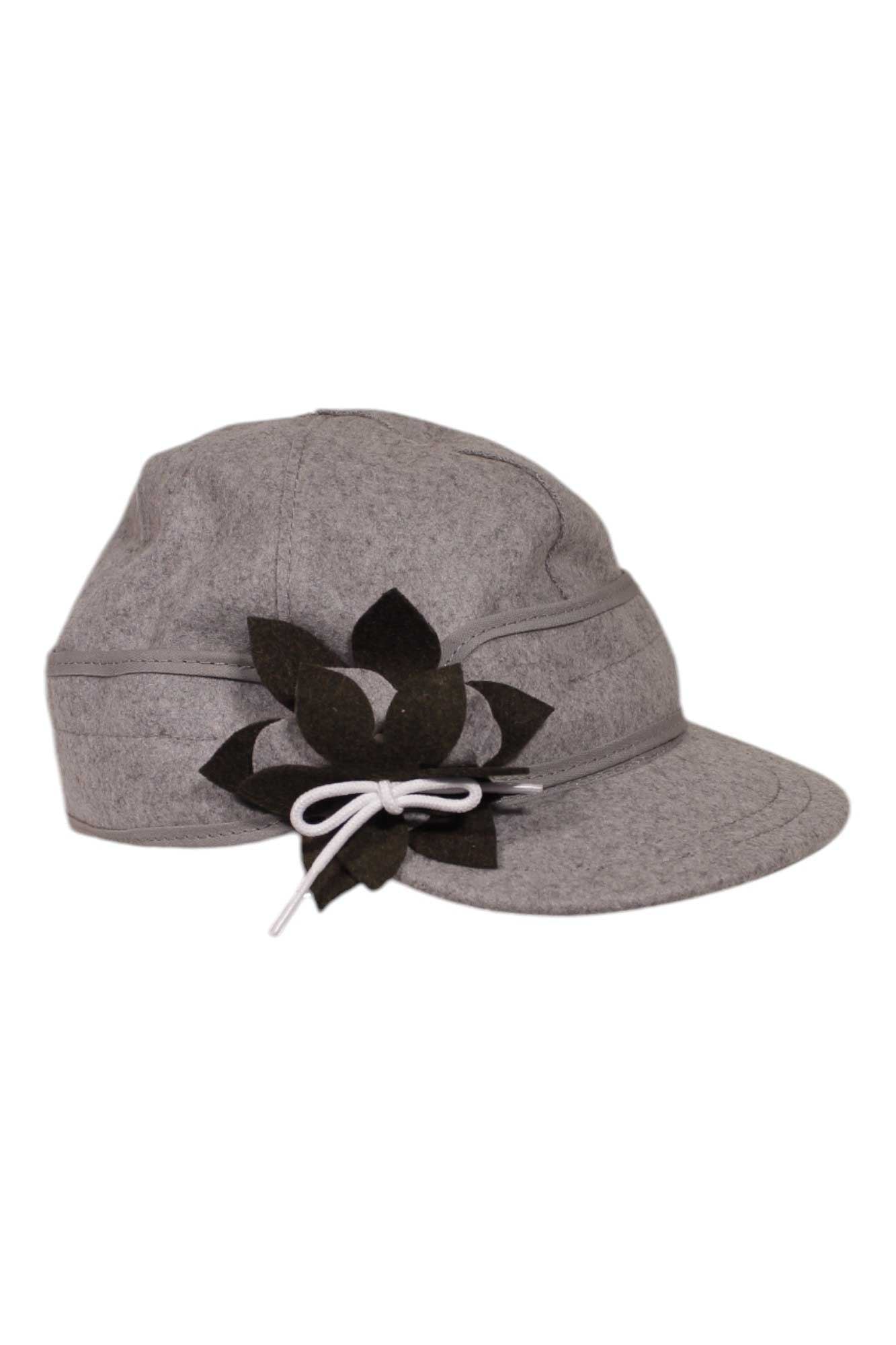The Stormy Kromer Womens Petal Pusher Cap is a gray casual hat with a curved brim, featuring a black felt flower and white string bow on the side for stylish sun protection—a modern twist on the classic petal pusher.