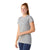 A woman with long red hair in a ponytail smiles while wearing the Smartwool Womens Merino SS Tee, slim fit and short sleeve in light gray, along with dark blue leggings, standing against a plain white background.
