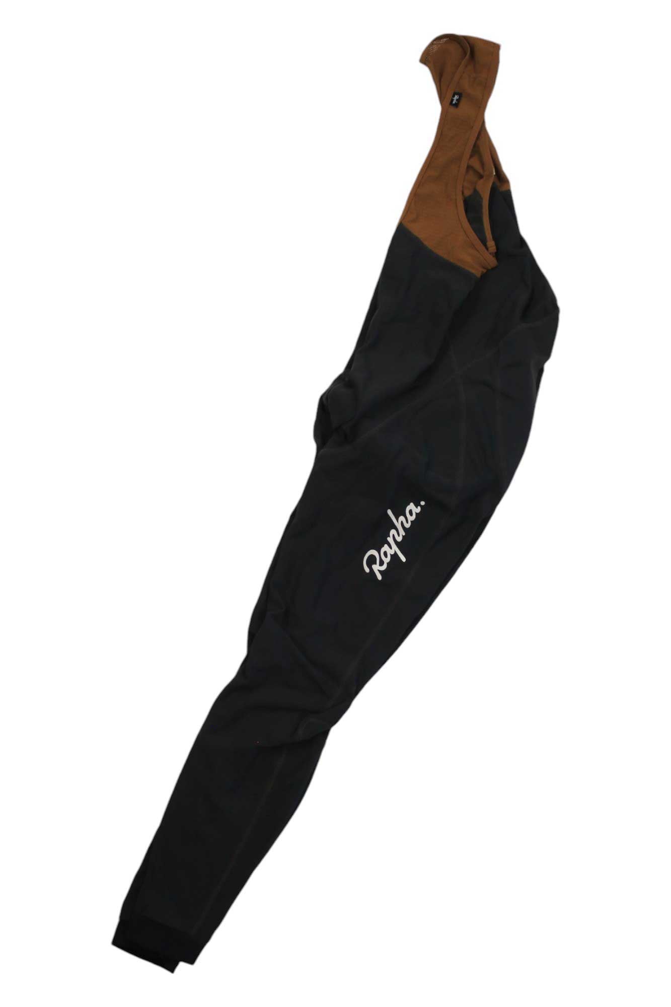 A pair of Rapha Mens Classic Winter Tights with Pad, featuring brown shoulder straps and a white Rapha logo on the left leg, are laid flat on a white background. Perfect for winter cycling.