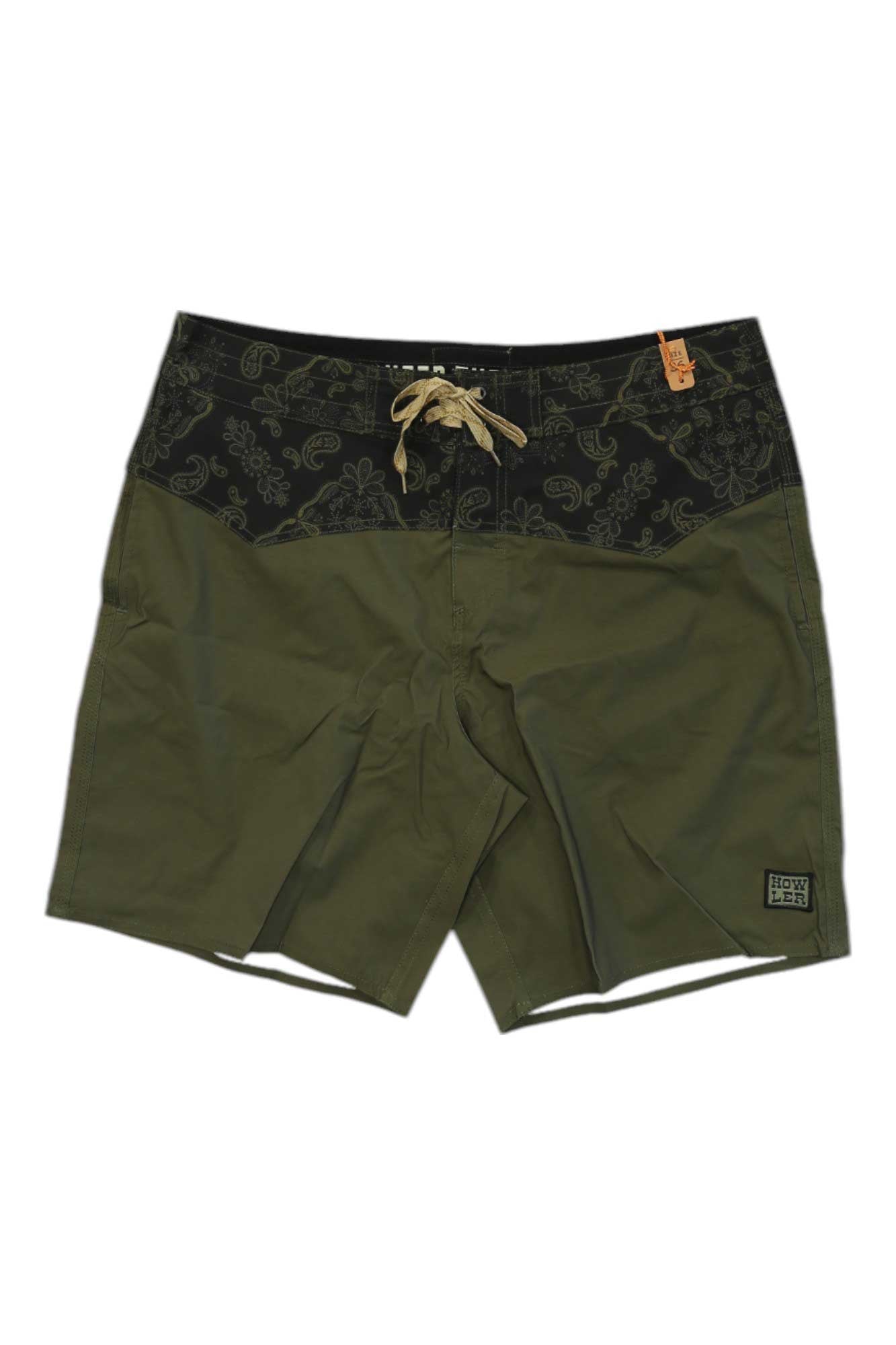 The Howler Brothers Mens Los Vaqueros Boardshort features olive green fabric, a black paisley-print waistband, beige drawstring, and a logo patch on the left leg—offering quick-drying comfort and style for any adventure.
