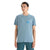A man with straight dark hair wears the Icebreaker Mens Tech Lite II SS Tee in light blue with a small circular logo on the left chest and teal pants, standing against a white background.