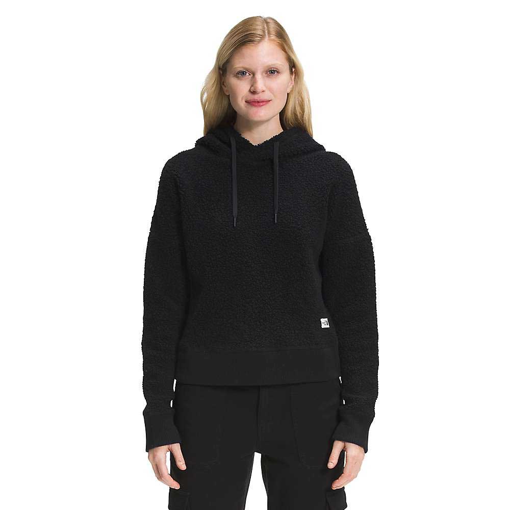 A blonde-haired woman wears The North Face Womens Wool Harrison Pullover Hoodie in black with matching pants, standing and smiling against a plain white background.