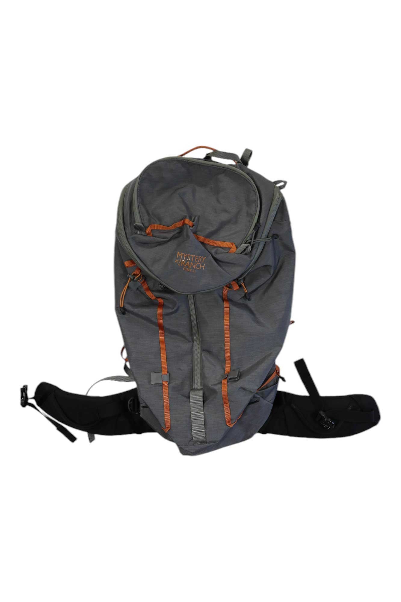 The Mystery Ranch Womens Scree 33 Backpack, a 33L gray hiking pack with orange accents and visible straps, features the brand name on the front and is shown against a white background.
