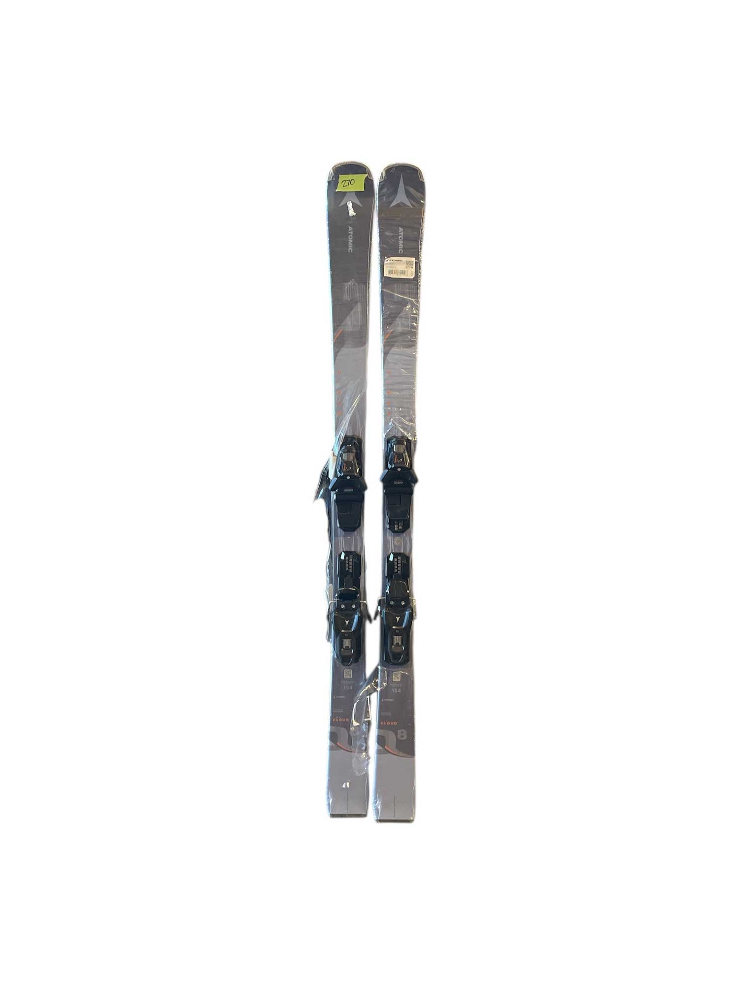 A pair of Atomic Women's Cloud Q8 skis with M10 GW Bindings, wrapped in protective plastic, stand upright side by side against a white background.