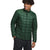 A young man with curly hair stands smiling to the side, wearing The North Face Men's ThermoBall Eco Jacket in dark green and dark pants. The jacket is made from recycled nylon. He poses against a plain white background.