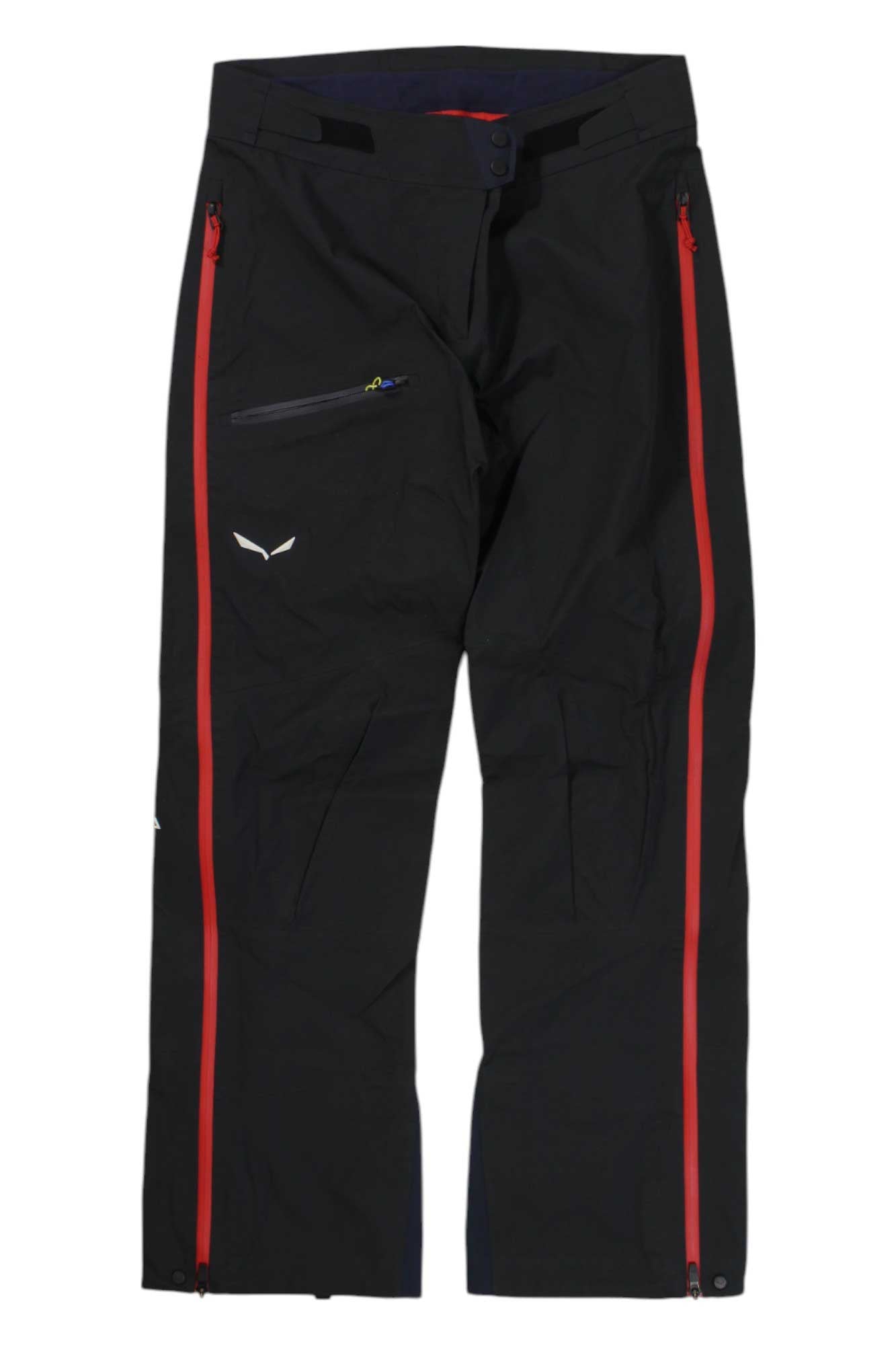 The Salewa Womens Ortles 2 GTX Pro Pant features black GORE-TEX Pro fabric, red side zippers, a right thigh zip pocket, and a small white logo on the left thigh—designed for alpine adventure with durable technical materials.
