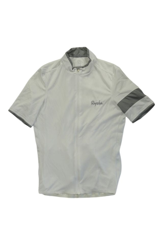 The Rapha Mens Super Lightweight Jersey is a short-sleeved, light gray cycling jersey with a front zipper, stand-up collar, dark gray stripe on the left sleeve, and Rapha embroidered on the chest.