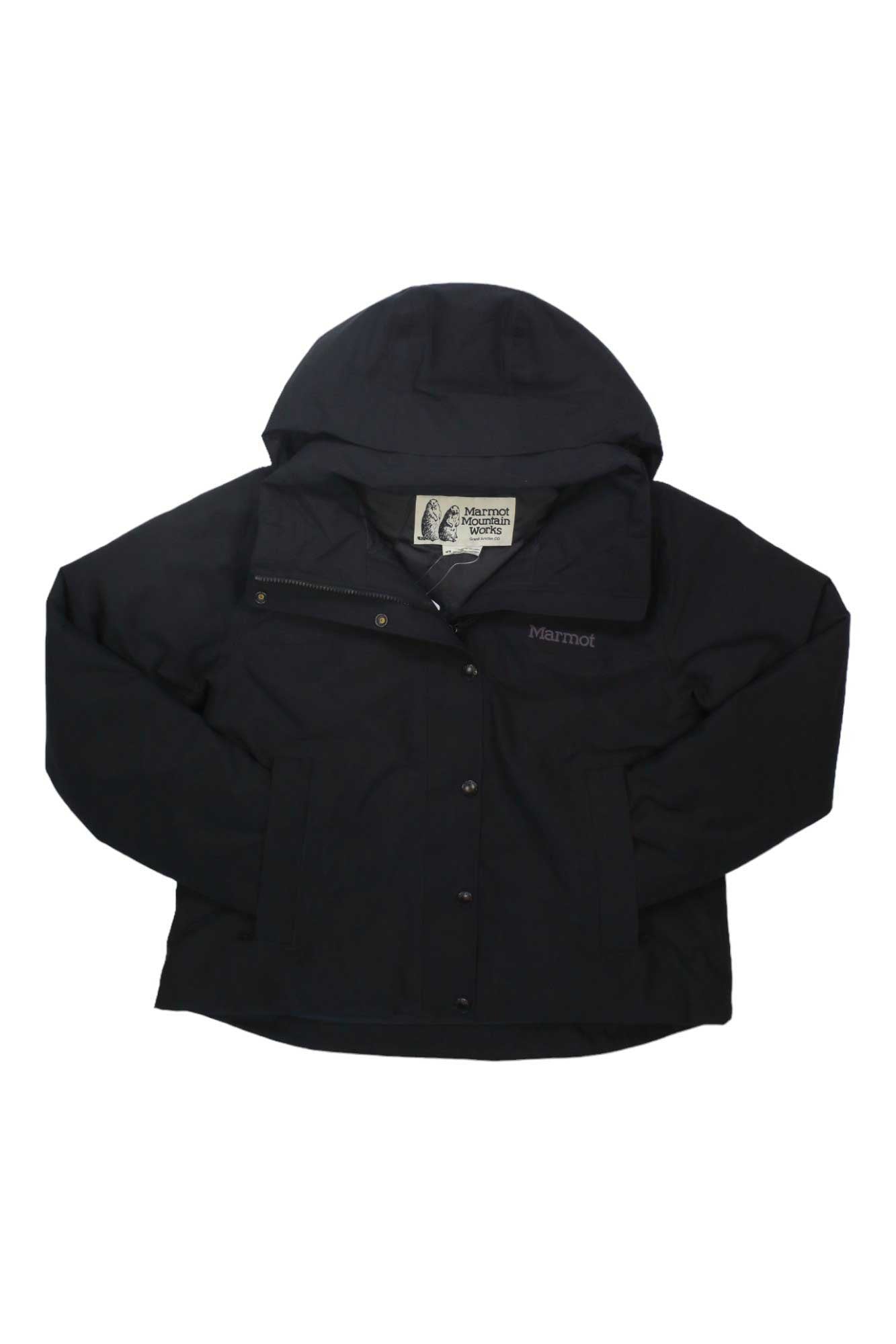 The Marmot Womens Chelsea Short Coat is a black waterproof hiking jacket for women, featuring a hood, zipper closure, buttons, and the Marmot logo on the chest.