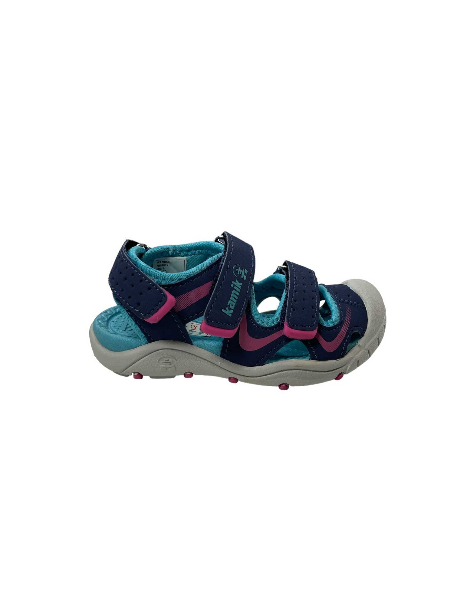 The Kamik Toddlers' Wander Sandal is a waterproof kids’ sandal in navy blue and teal with pink accents, featuring an adjustable hook and loop strap. Shown for toddlers on a white background.