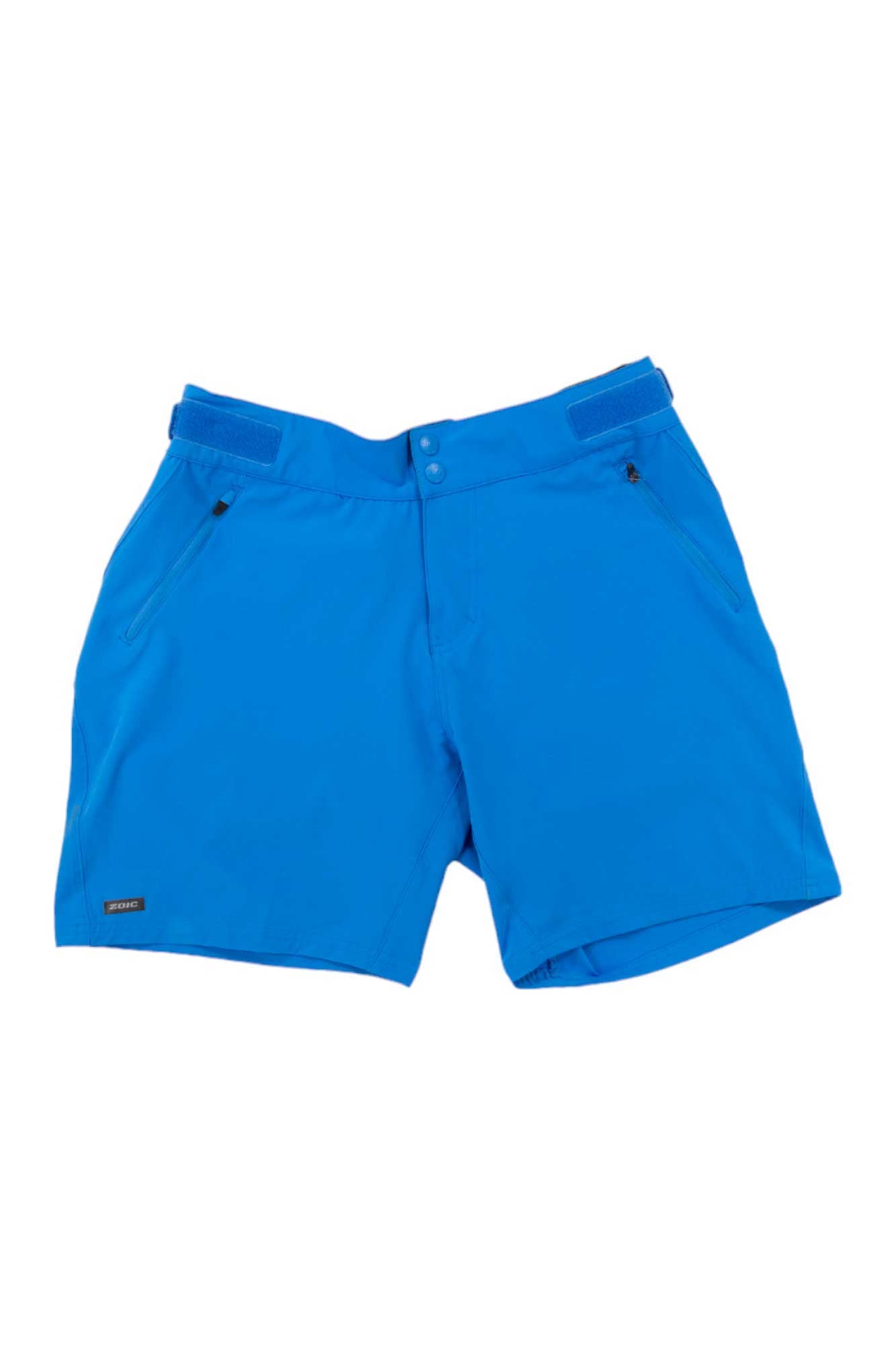 The Zoic Womens Navaeh 7 Short in bright blue features side zipper pockets, belt loops, and a front button closure. Displayed on a white background, these packable cycling shorts offer style and functionality for active women.