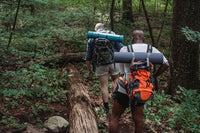 two men with backpacks hiking in the woods