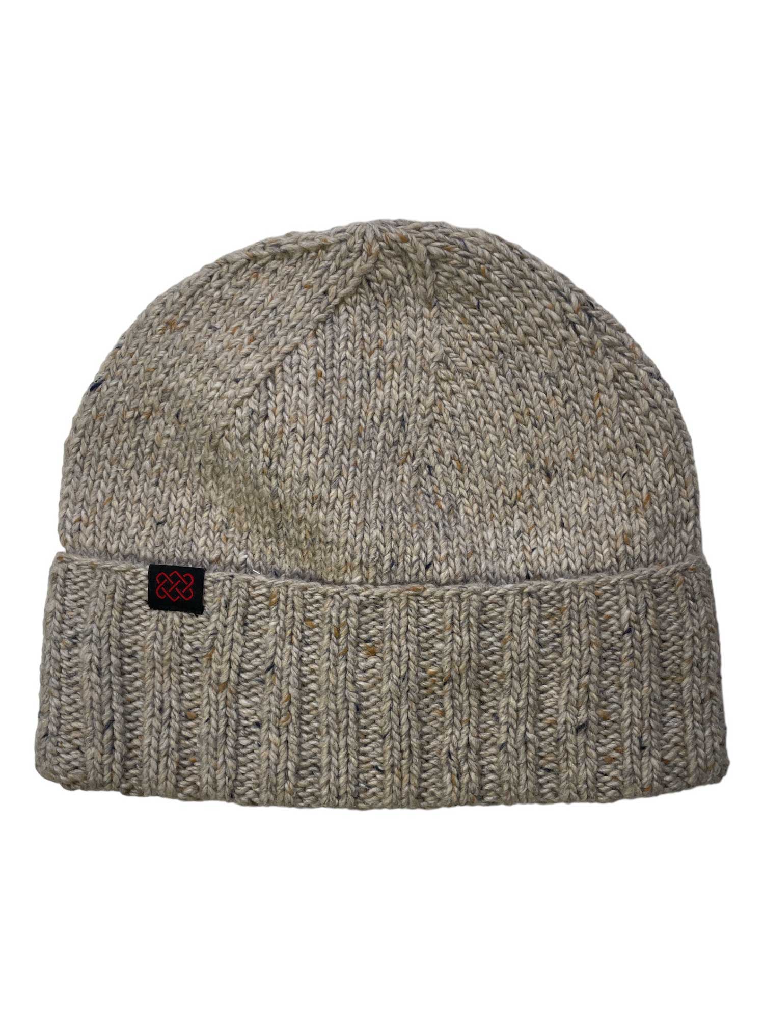 The Sherpa Vishnu Hat is a handcrafted gray unisex Merino wool beanie with subtle multicolor speckles, a folded brim, and a small black patch with a red design on the cuff.