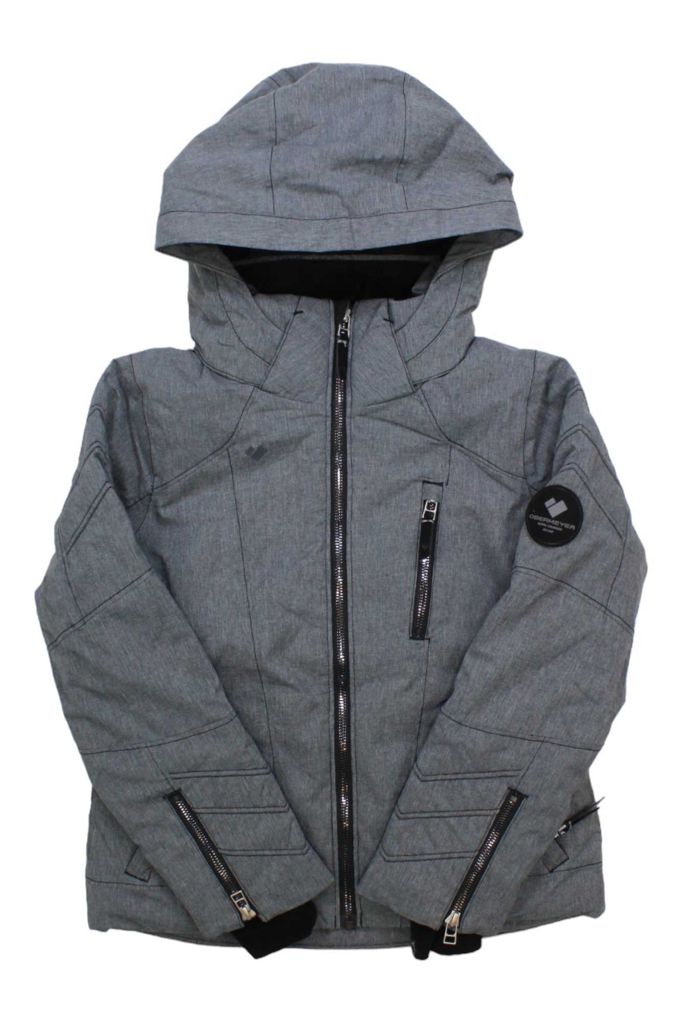 Obermeyer Girls Rayla Ski Jacket: Gray insulated winter jacket with hood, black zippers, front pockets, and a round patch on the left sleeve. Modern, structured ski jacket displayed against a white background.
