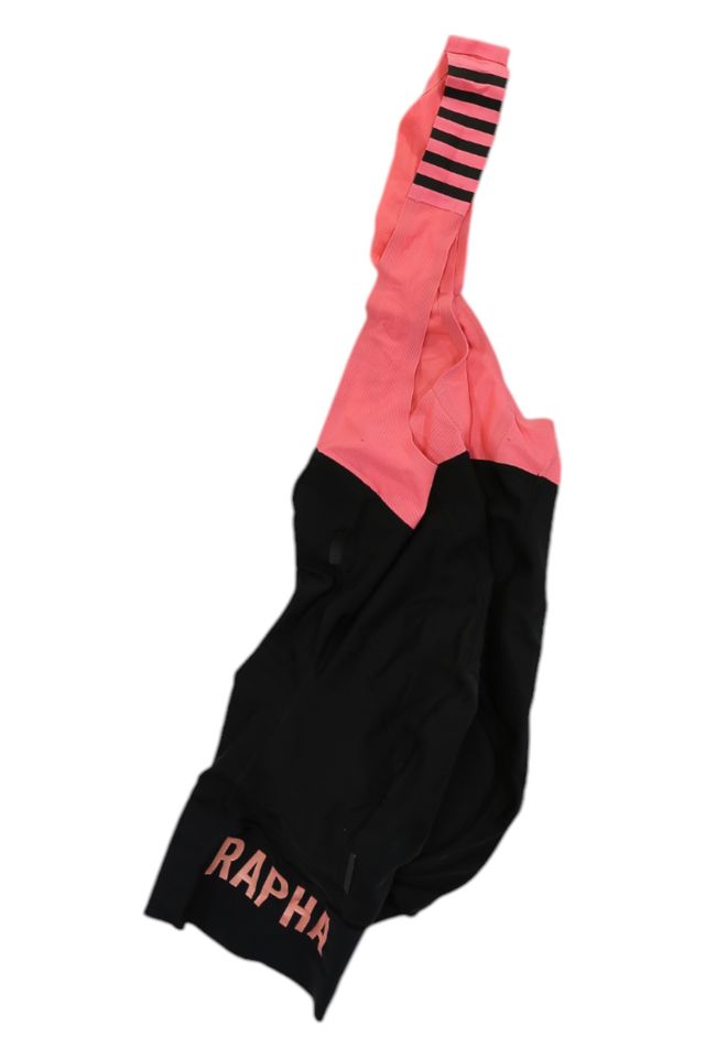 The Rapha Mens Pro Team Bib Shorts II - Regular feature a black lower half, pink upper straps, RAPHA in pink on the leg band, black stripes on a pink strap, and a race-grade chamois for maximum comfort.