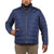 A man wears the Moosejaw Mens Down Insulator Jacket in blue—a water-resistant, responsibly sourced down jacket with a zip-up front and standing collar. He has one hand in his pocket and pairs it with light brown pants.