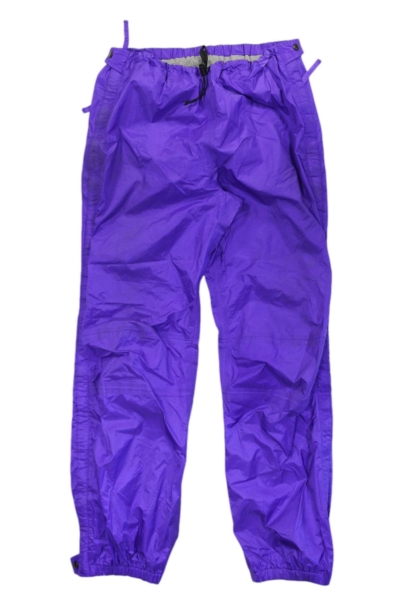 The Full-Zip Retro Soft Shell Pants in bright purple feature lightweight nylon, an elastic waistband with drawstring, elastic cuffs, and a slightly crinkled texture—ideal for outdoor adventures—shown laid flat on a white background.