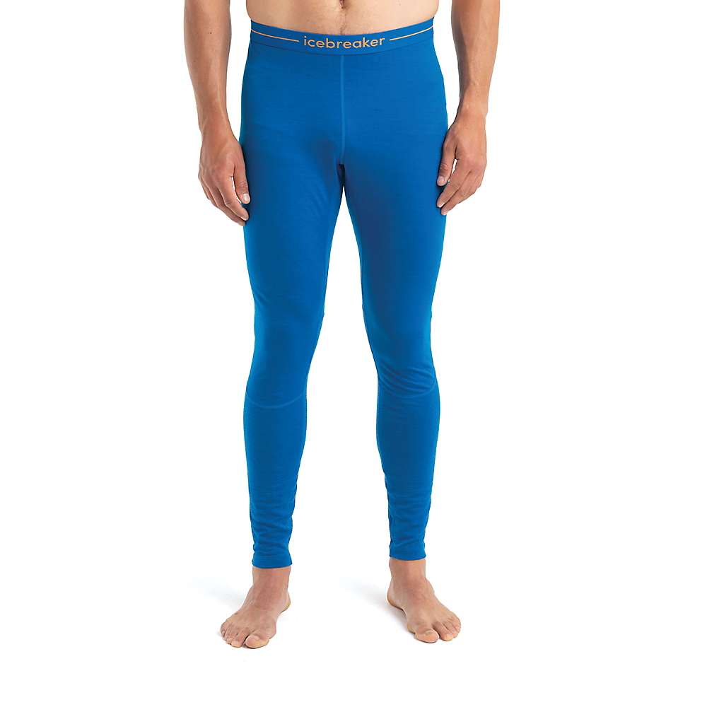 A barefoot person wears Icebreaker Men's 200 Zoneknit Legging in bright blue, featuring a form-fitting merino wool design and branded waistband. The cropped image shows only the lower torso and legs. Ideal for temperature regulation.