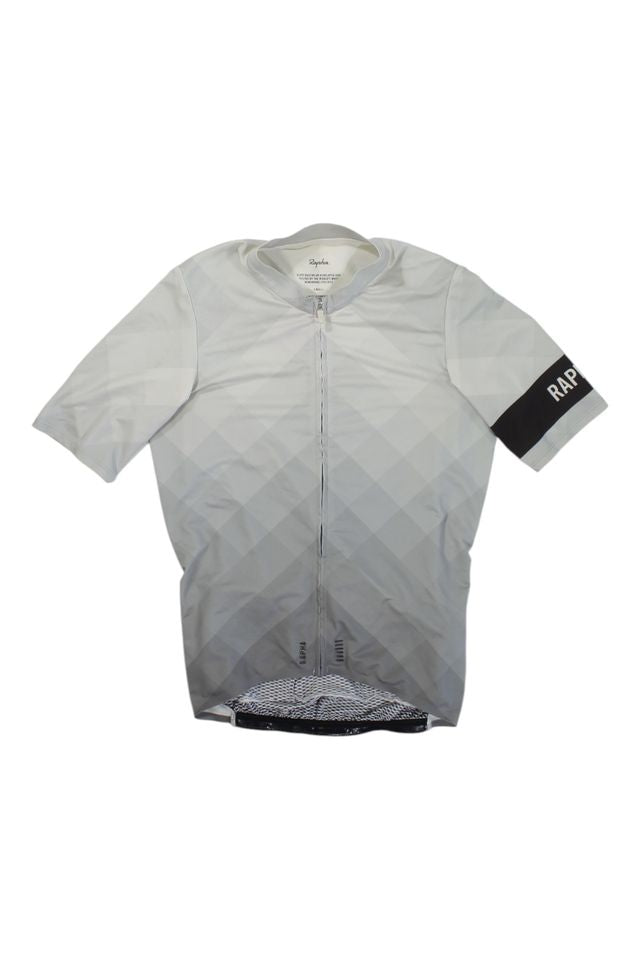 The Mens Pro Team Midweight Short Sleeve Jersey is a light gray cycling jersey with a geometric pattern, full front zipper, and black left armband with white RAPHA text—ideal for versatile rides.