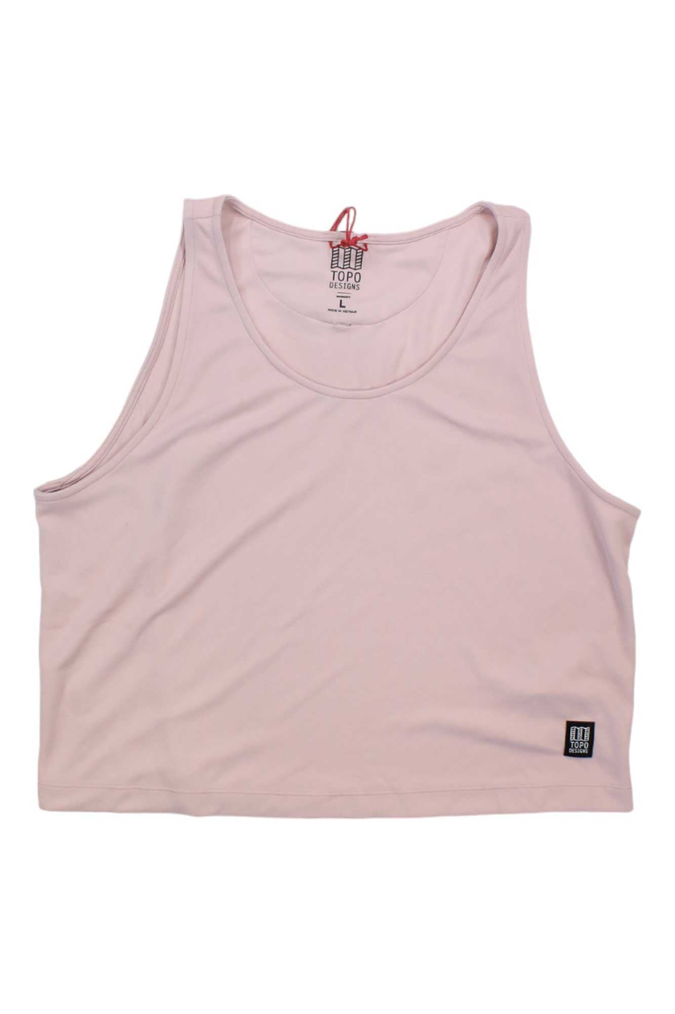 The Topo Designs Womens River Tank is a light pink sleeveless crop top with a round neckline and a rectangular black and white logo patch near the hem, designed for all-day comfort during outdoor adventures.