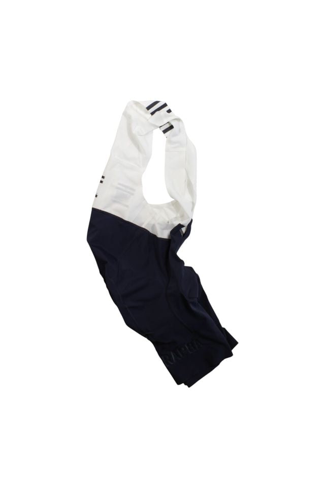 A pair of Rapha Mens Pro Team Bib Shorts II - Regular with a race-grade chamois, white shoulder straps, and a dark navy lower section, shown on a plain white background.