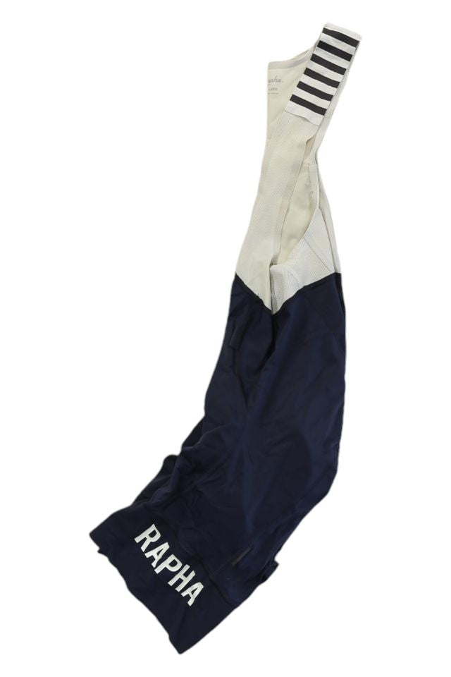Navy blue and white Rapha Mens Pro Team Bib Shorts II - Regular with RAPHA in white on the leg, striped shoulder straps, and a race-grade chamois for comfort on long rides.