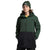 A person wearing The North Face Mens Freedom Stretch Jacket in green and black with a matching green beanie, standing hands in pockets against a white background.
