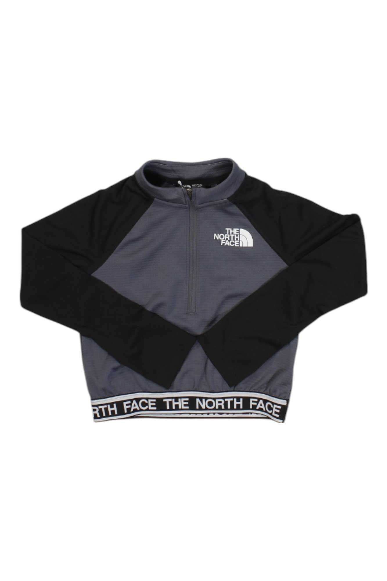 The North Face Girls Reactor Thermal 1/4 Zip Top is a gray, long-sleeve athletic top with black sleeves, made from recycled polyester. It features a left chest logo and "THE NORTH FACE" text on the waistband.