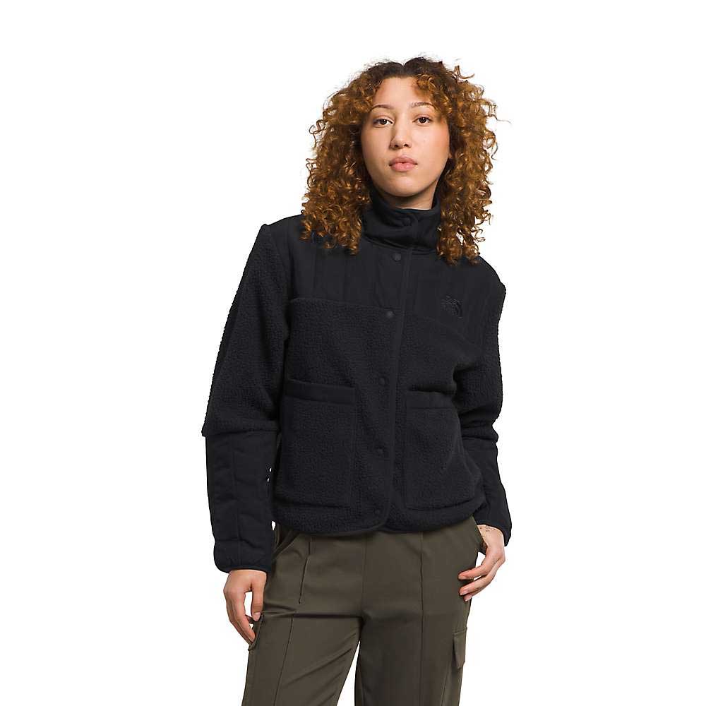 A woman with curly hair wears The North Face Womens Cragmont Fleece Jacket over olive green pants, standing against a plain white background with a neutral expression.