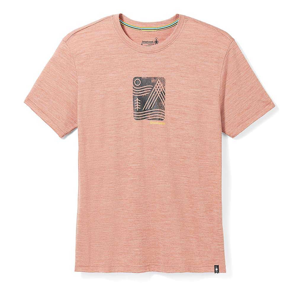 The Smartwool Mountain Breeze Graphic SS Tee is a light pink, short-sleeve Merino wool shirt with superior moisture management and a minimalist dark gray and white mountain, tree, and sun or moon graphic. Laid flat on a white background.