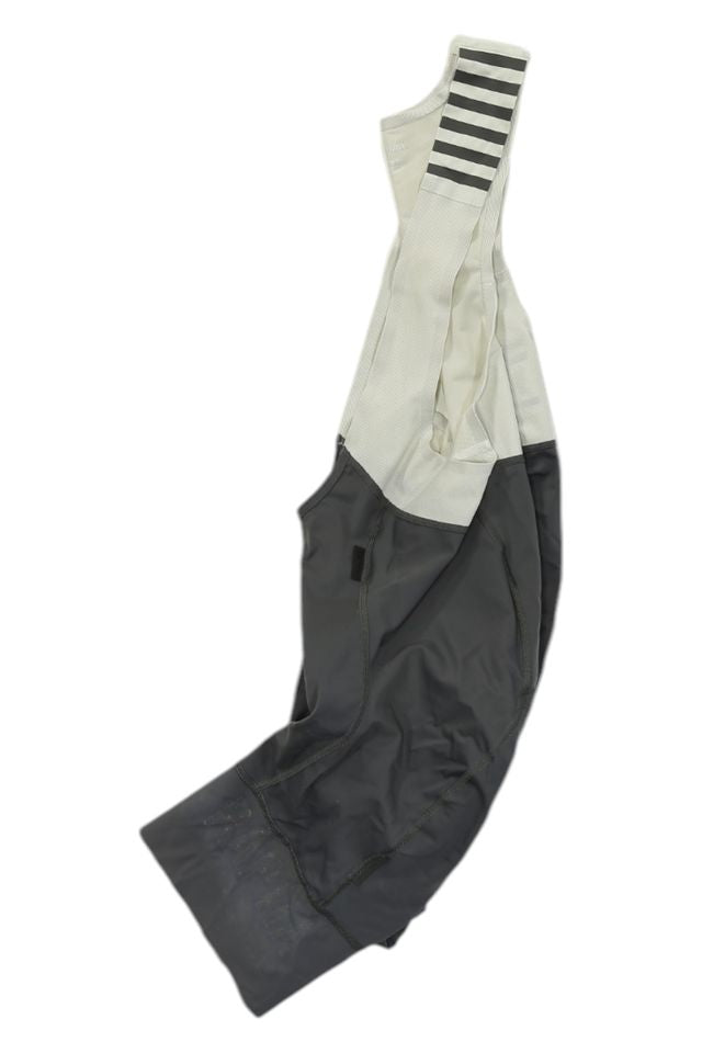 A pair of Rapha Mens Pro Team Bib Shorts II - Regular with race-grade chamois, black and white design, and black horizontal stripes on one strap, shown laid flat on a white background.