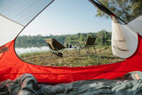 A view of camping chairs from inside a tent