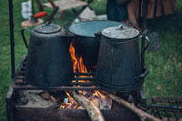 Two kettles and a pot over a fire