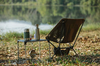 A camp chair and side table in front of a lake