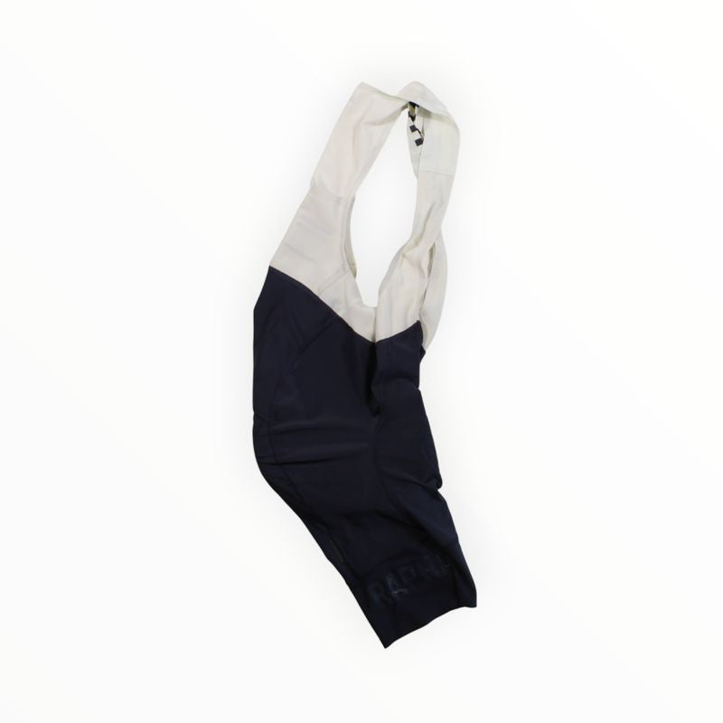 Navy blue and white Rapha Mens Pro Team Bib Shorts II - Regular with race-grade chamois, laid flat on a white background, shoulder straps extending upward.