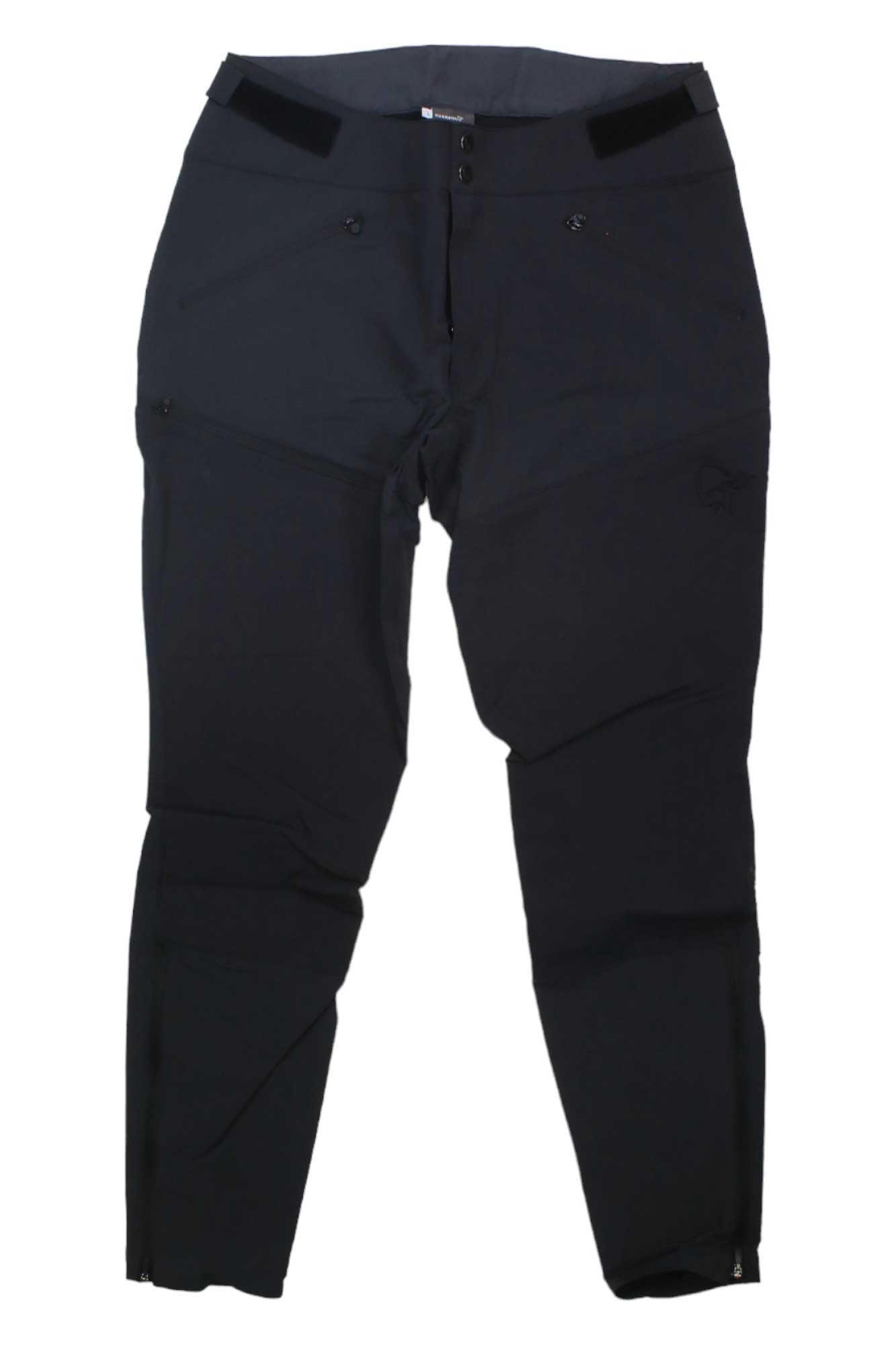 The Norrona Womens Falketind Rugged Slim Pant—black, slim-fit softshell pants with a zippered front, button closure, and side pockets—are versatile, all-year outdoor pants for style and performance. Shown laid flat on a white background.