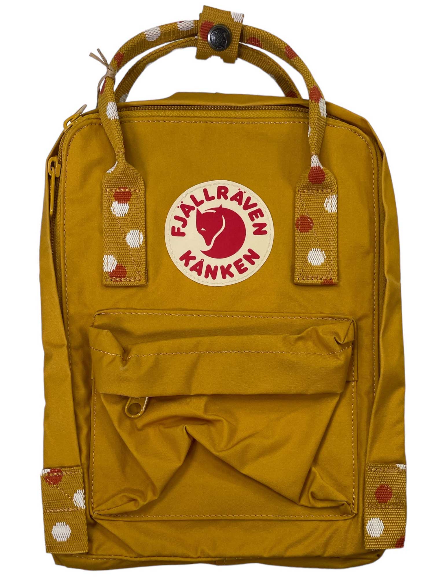 The Kanken Mini Pack is a mustard yellow backpack with a front pocket, adjustable shoulder straps, top handles with a white and red spotted pattern, and a circular red and white reflective fox logo on the front.