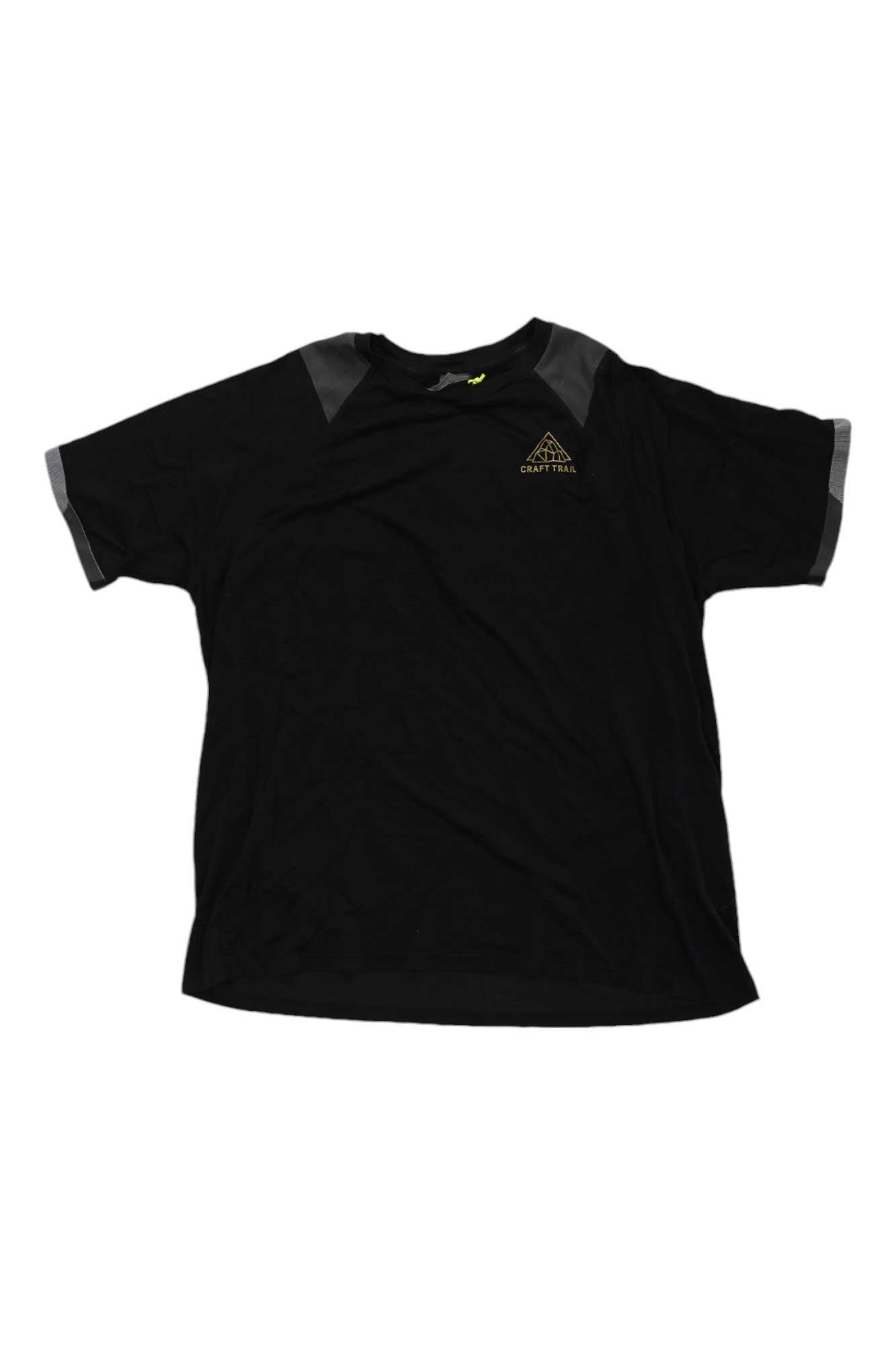 The Craft Sportswear Mens Pro Trail Fuseknit SS Tee is a black, ultra-lightweight men's shirt with gray shoulder and sleeve panels, a small yellow geometric logo, and text—ideal for trail running or as moisture-wicking activewear.
