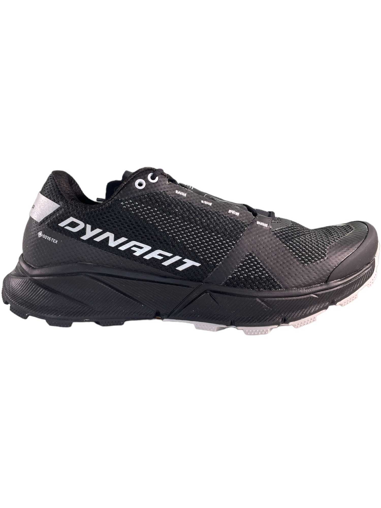 The Dynafit Men's Ultra 100 GTX Shoe is a black athletic trail runner featuring a mesh texture, white side logo, and rugged sole—ideal Gore-Tex footwear for running or challenging trail activities.