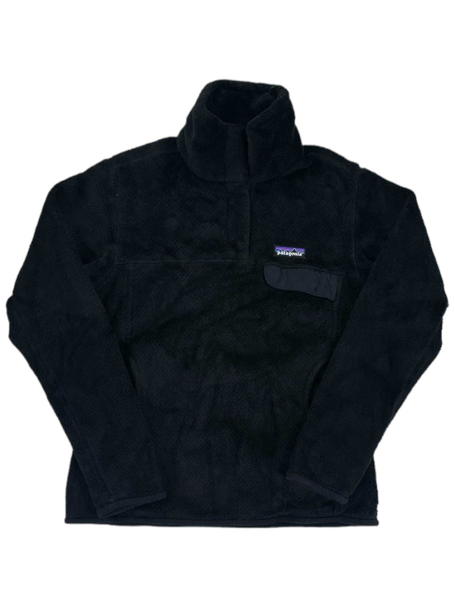 The Women's Re-Tool Snap-T Pullover is a black Polartec Thermal Pro fleece with long sleeves, high collar, and chest pocket with a Patagonia logo patch. Made from recycled polyester, it’s soft, warm, and Fair Trade Certified.
