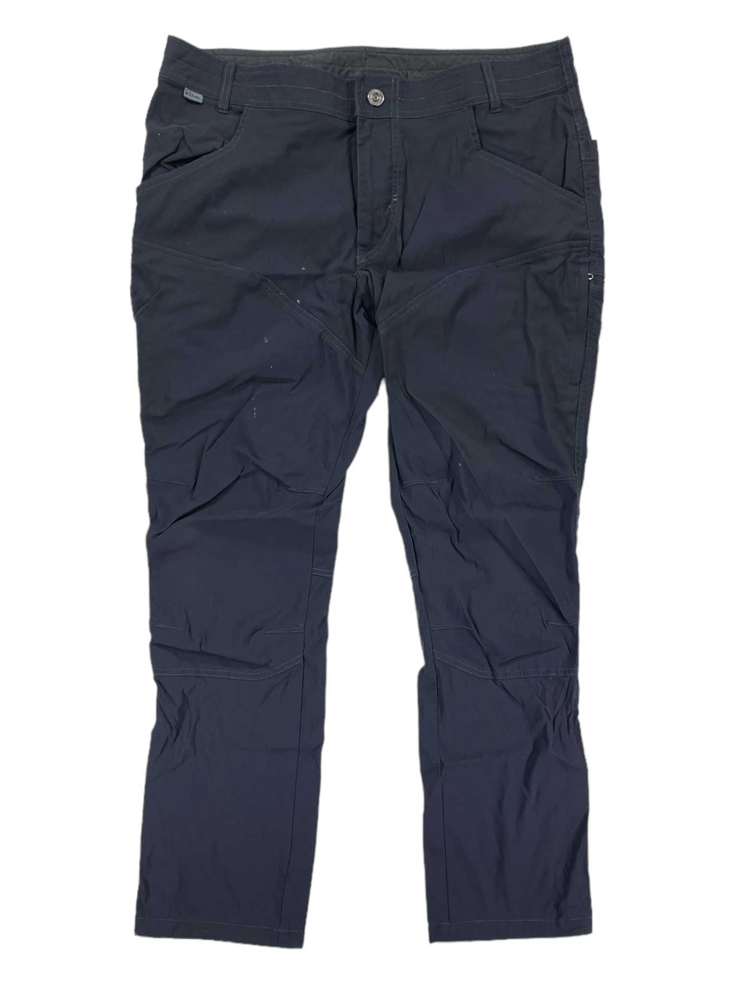 A pair of Mens Renegade Rock Pants in dark navy blue, made from stretch softshell fabric with front and side pockets, button and zipper closure, laid flat on a white background. The pants appear slightly wrinkled.