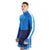 A young man stands against a plain white background, wearing the Icebreaker Mens 260 Zoneknit LS Half Zip Top in blue with a zip collar and white sleeve stripe, paired with blue running shorts.