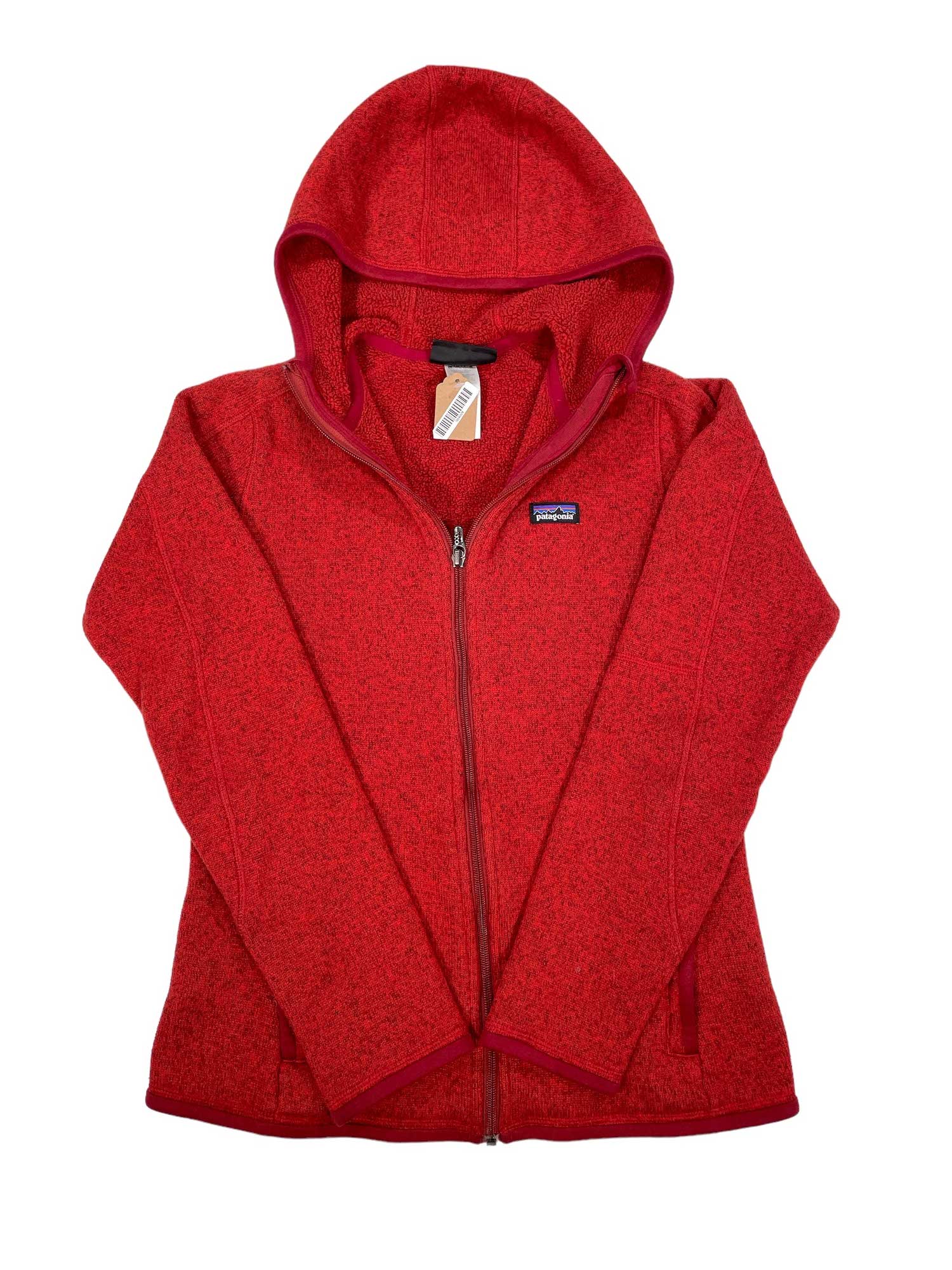 The Womens Better Sweater Full-Zip Hoody is a red hooded jacket made from recycled polyester fleece, with long sleeves, front pockets, and a small chest logo patch. It’s shown laid flat with the hood up and a tag on the zipper.
