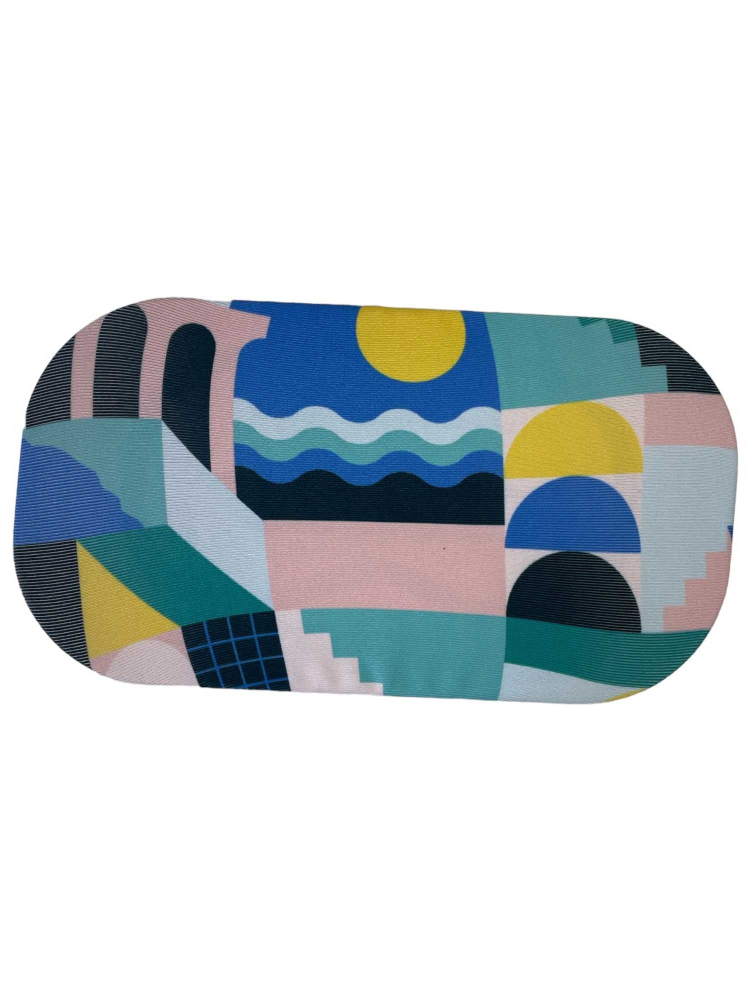 The GoggleSoc Protective Goggle Cover is a rectangular, eco-friendly cover with rounded edges and an abstract geometric design—showcasing arches, waves, stairs, circles, and bold shapes in blue, yellow, pink, green, and black.