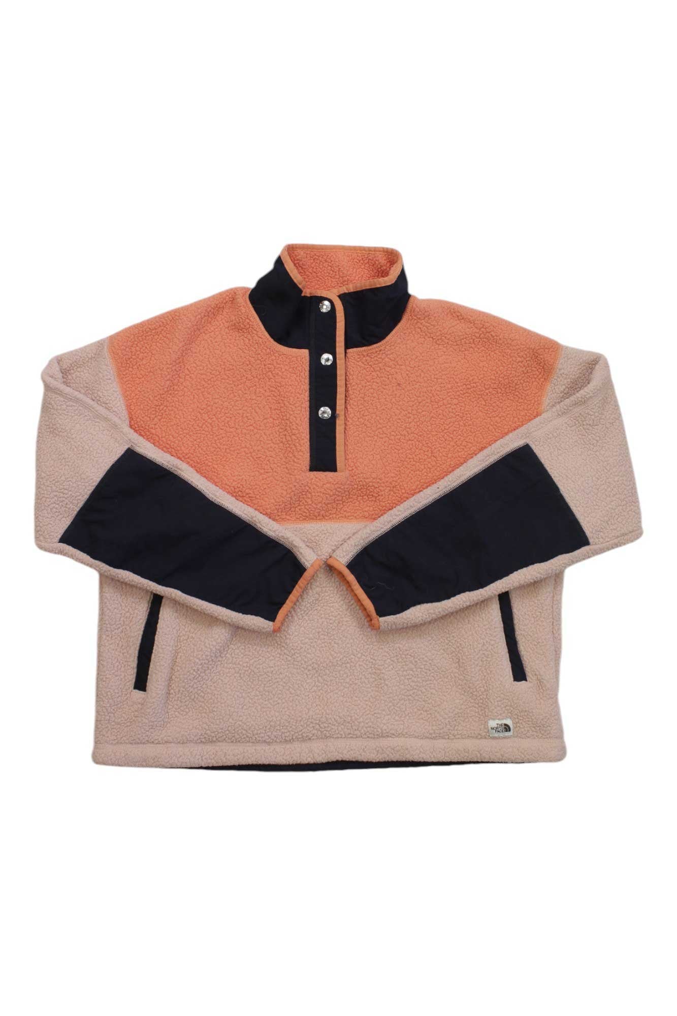 The North Face Womens Cragmont Fleece 1/4 Snap Top features peach, beige, and black color-blocking, a high collar, quarter snap front, two zippered pockets, and is made from recycled polyester for sustainable comfort.