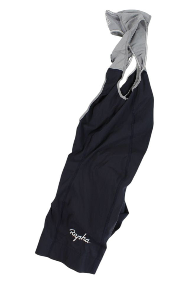 Mens Bib Shorts in black and gray with "Rapha" in white script on one leg, shown flat on a white background—an essential piece of cycling apparel.