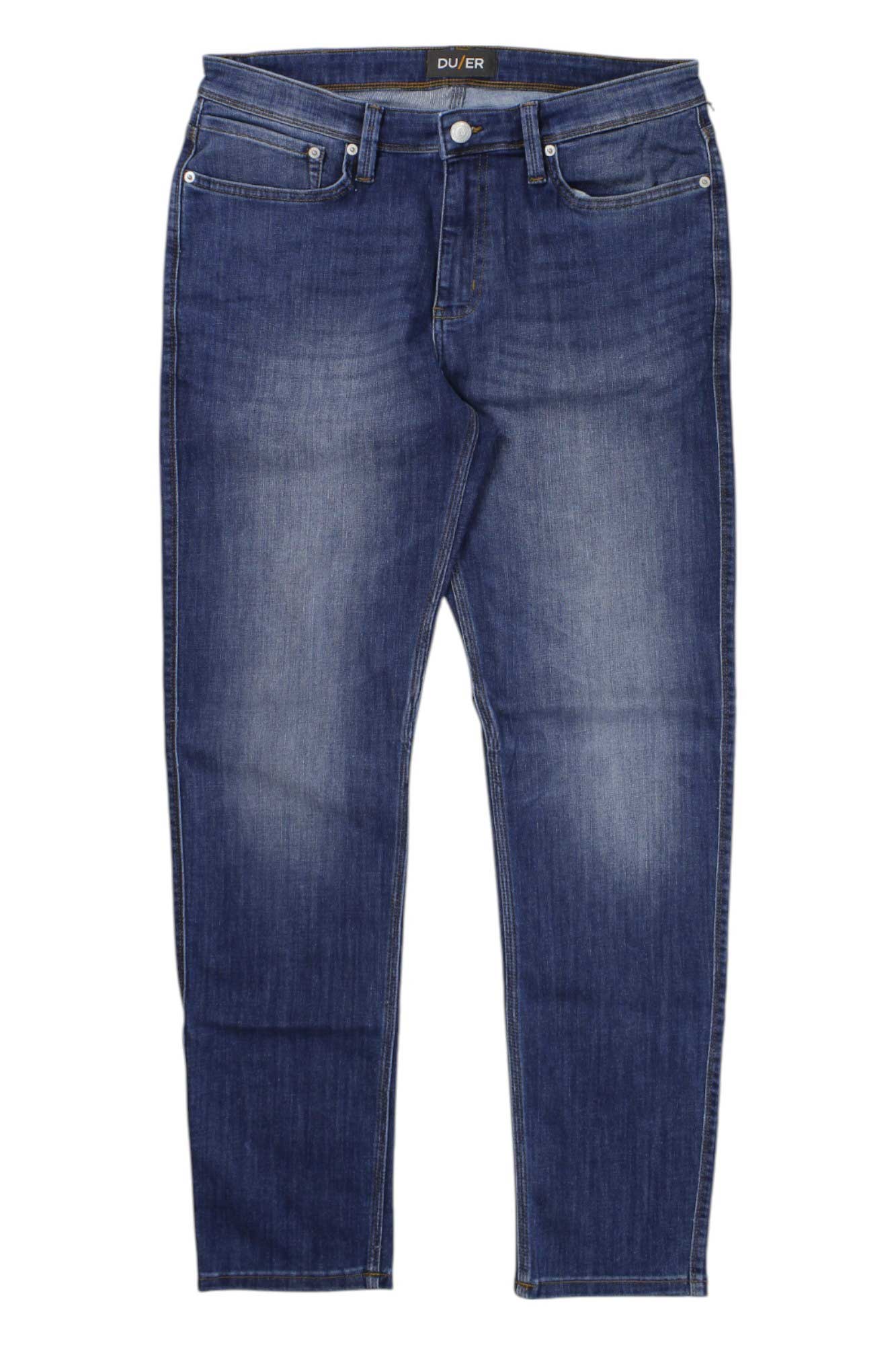 The DU/ER Men's Performance Denim Jean - Slim Fit in dark blue features a fitted cut, front and back pockets, and button-zipper closure. Jeans are displayed flat on a white background.