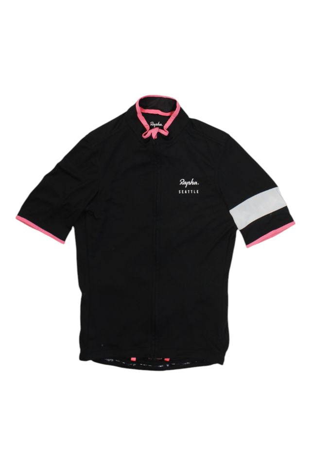 The Rapha Mens Super Lightweight Jersey is a black, short-sleeve cycling jersey with pink trim on the collar and sleeves, a white band on the left sleeve, and 'Rapha Seattle' on the left chest.