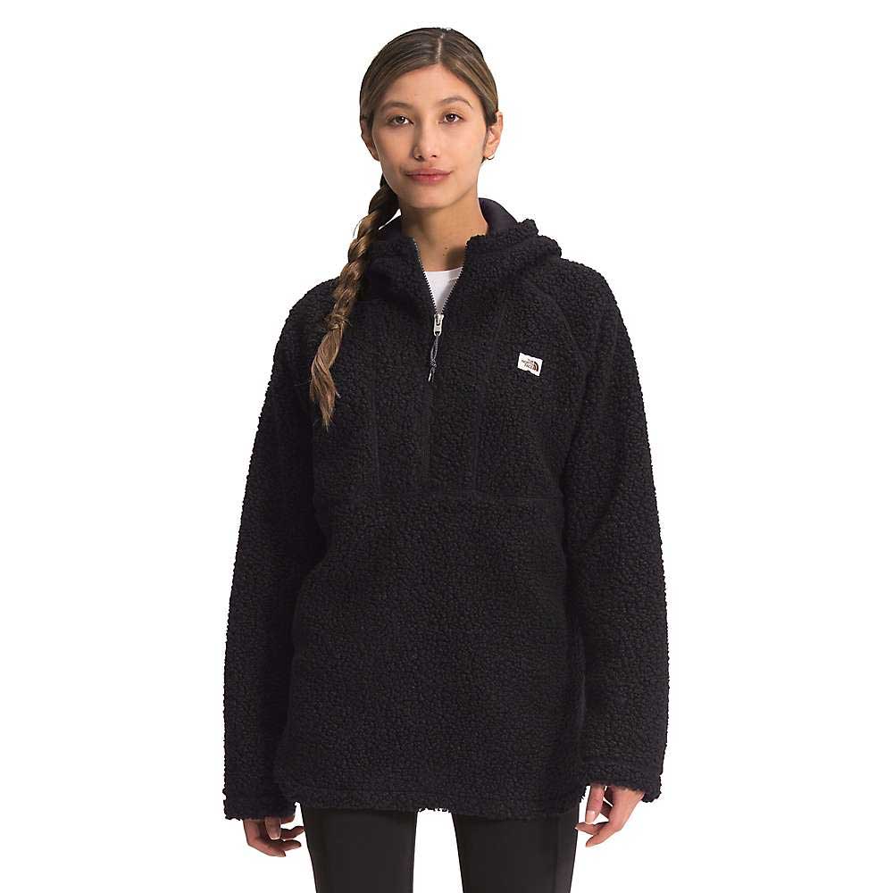 A woman with a long braid wears the Womens Ridge Fleece Tunic, featuring an eco-friendly black textured finish, quarter-zip, and hood. She stands facing forward against a plain white background.