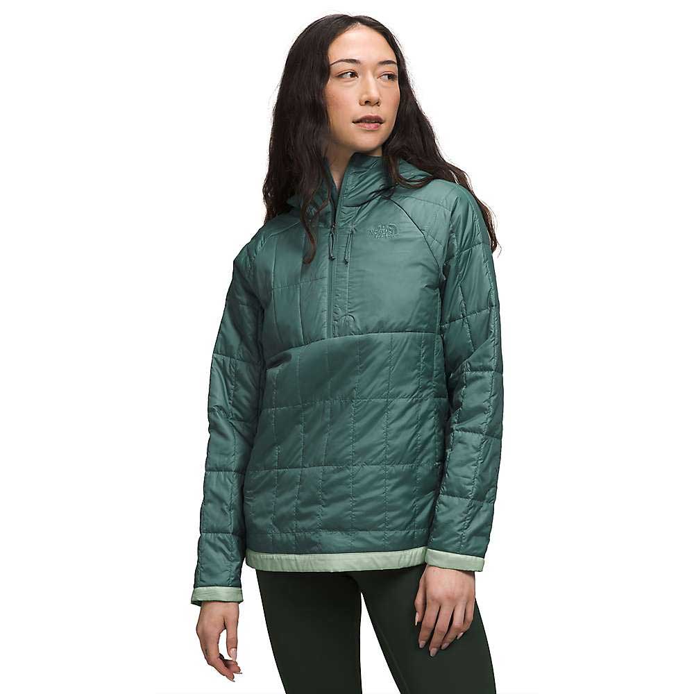 A woman models The North Face Womens Circaloft 1/4 Zip Pullover in teal with synthetic insulation and a high collar, standing against a white background, facing slightly left with hands relaxed at her sides.
